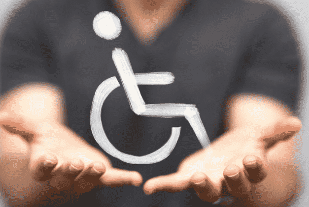 Symbole du handicap entre les deux mains d'un ostéopathe.